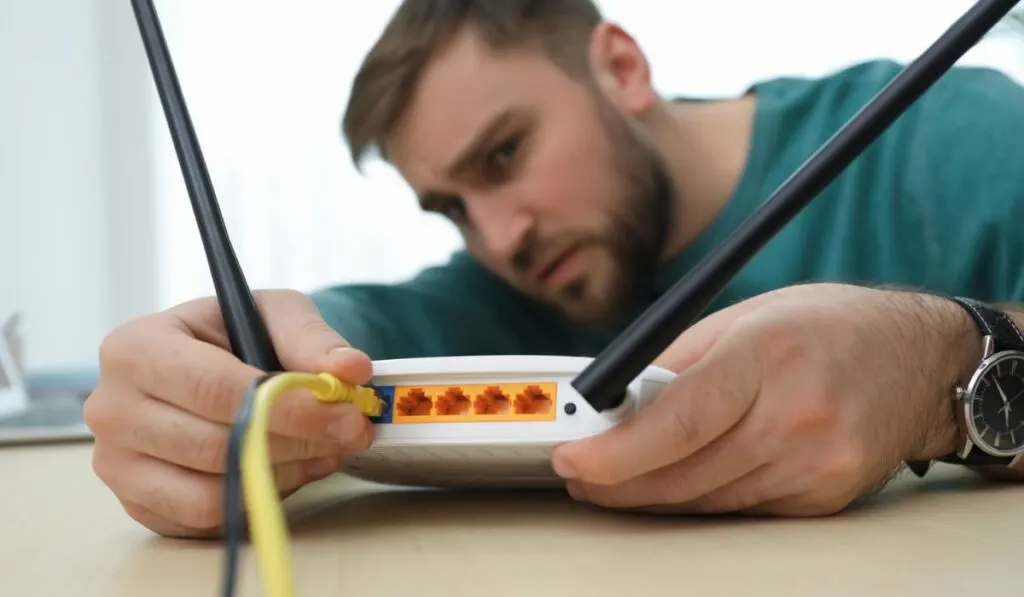 Man connecting cable to router at table