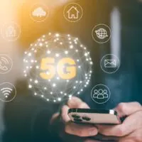 Man hold smartphone with Global network connection 5G virtual interface screen on laptop device