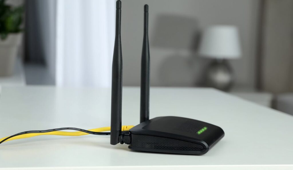 Modern Wi-Fi router on white table in room