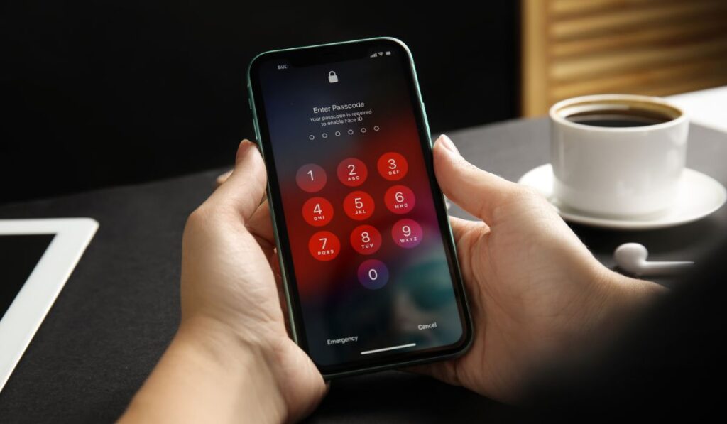 Woman holding Iphone 11 with numpad for entering passcode on screen at black table