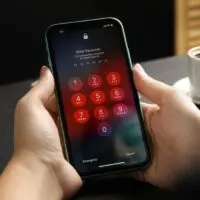 Woman holding Iphone 11 with numpad for entering passcode on screen at black table