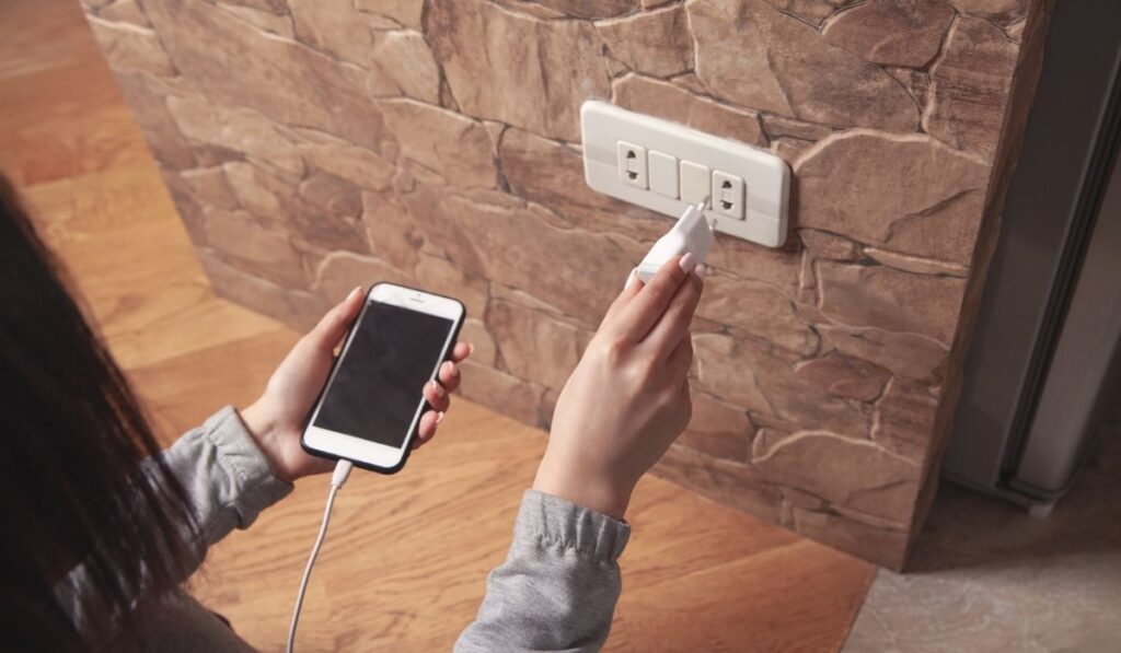 Woman plugs the phone charger into the socket