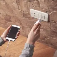 Woman plugs the phone charger into the socket
