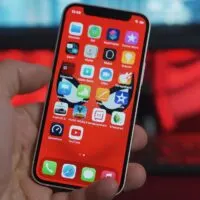 Hand holding iPhone 12 mini on colorful background