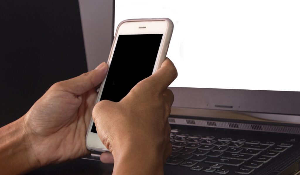 Руки, которые касаются телефона с черным экраном, чтобы работать дома в Интернете