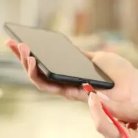 Woman hand plugging battery charger on phone