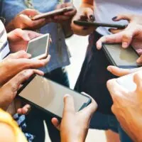 Young adult friends using smartphones together outdoor