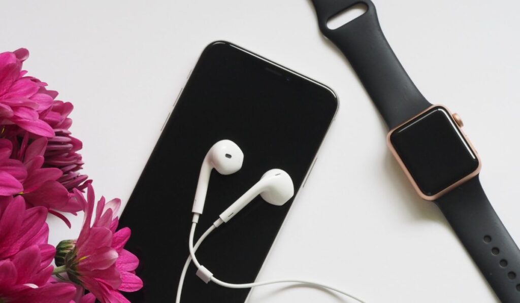 Close-Up Photography of Earphones on Top of Iphone 6 Near Flowers