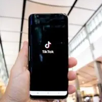 Hand of man holding mobile phone opening Tik Tok application
