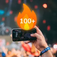 Phone recording concert with fire emoji showing 100+ on it