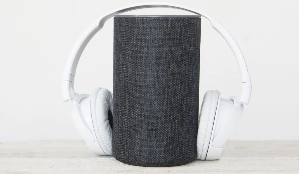 Smart speaker Amazon Alexa Echo device next to some books and hearphones against a white background