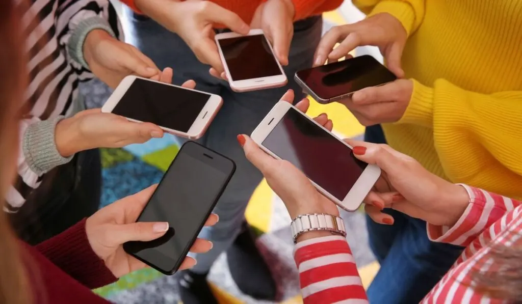 Young people with mobile phones standing in circle