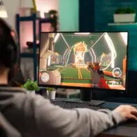 Adult playing video games on monitor with mouse