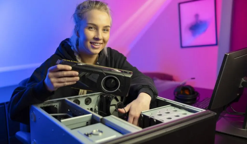 Smiling E-sport Gamer Girl Installing New GPU Video Card in Her Gaming PC