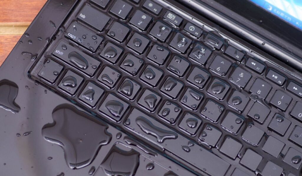 Выше вид ноутбука с каплей воды, поврежденной жидкостью, мокрой и пролитой на клавиатуру