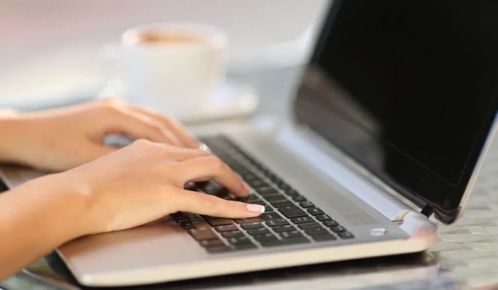 Woman hands working with a laptop in a coffee shop