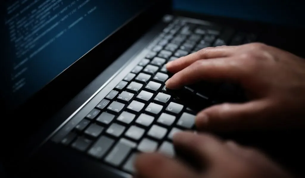 Программист или компьютерный хакер печатает на клавиатуре ноутбука