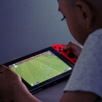 Young boy playing on a Nintendo Switch with a soccer field on the screen